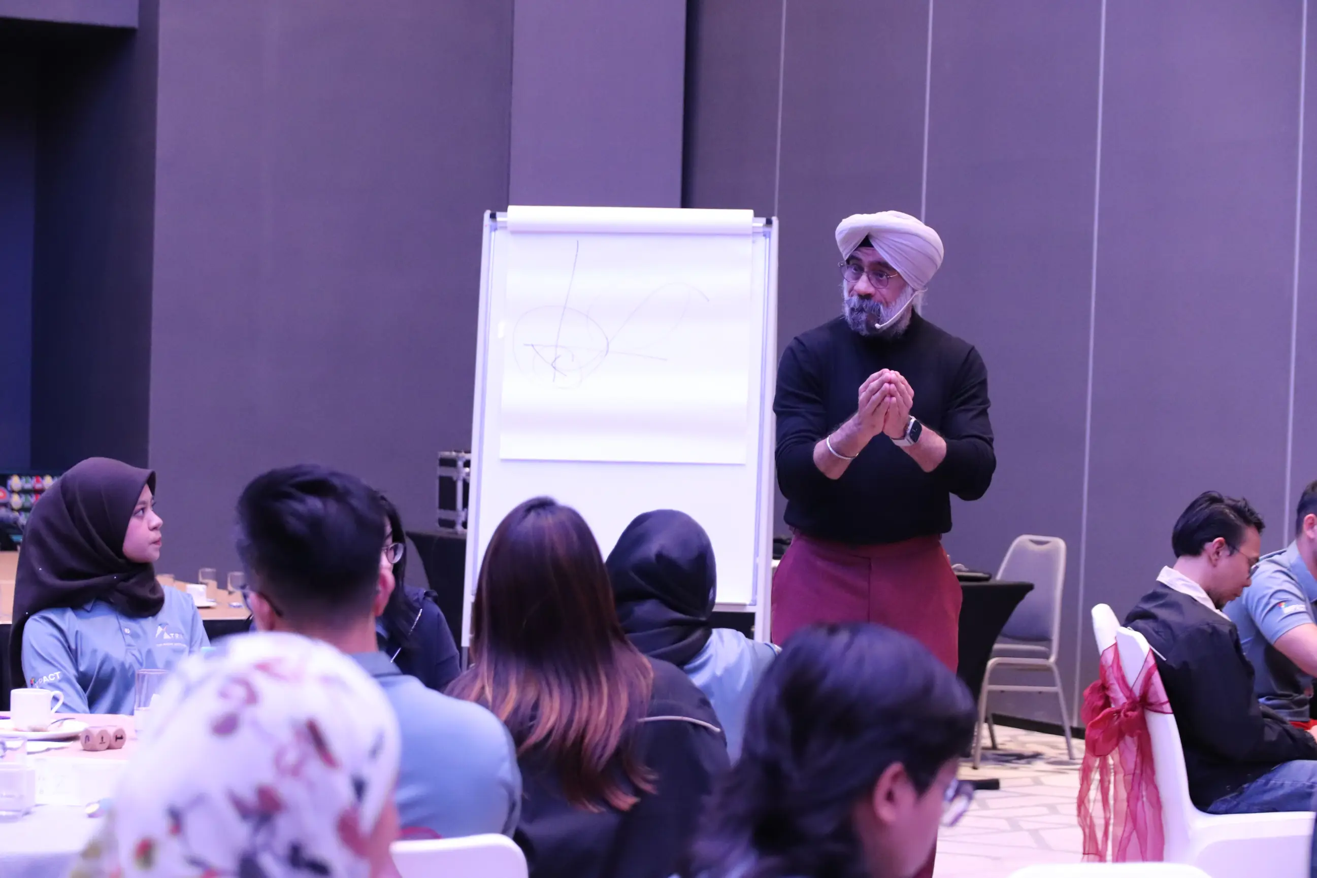 A Learning Edge facilitator leading a live team session with a seated cohort gathered around a flipchart